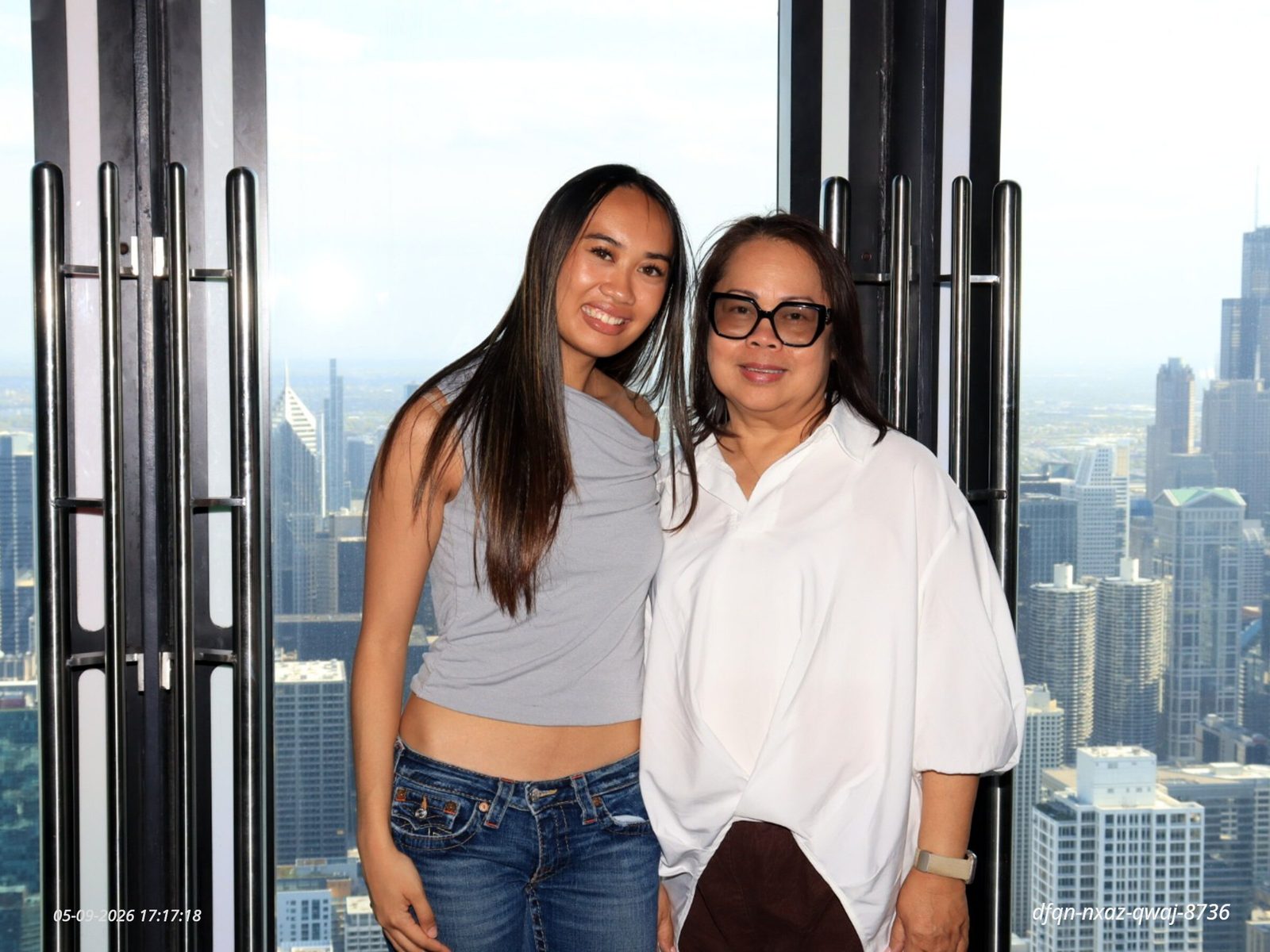 Genalyn and a young woman standing at a window high above the Chicago skyline