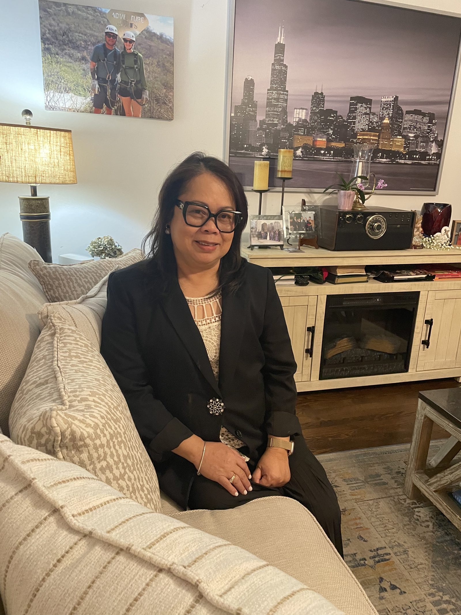 Genalyn seated on a sofa in a dark blazer, smiling